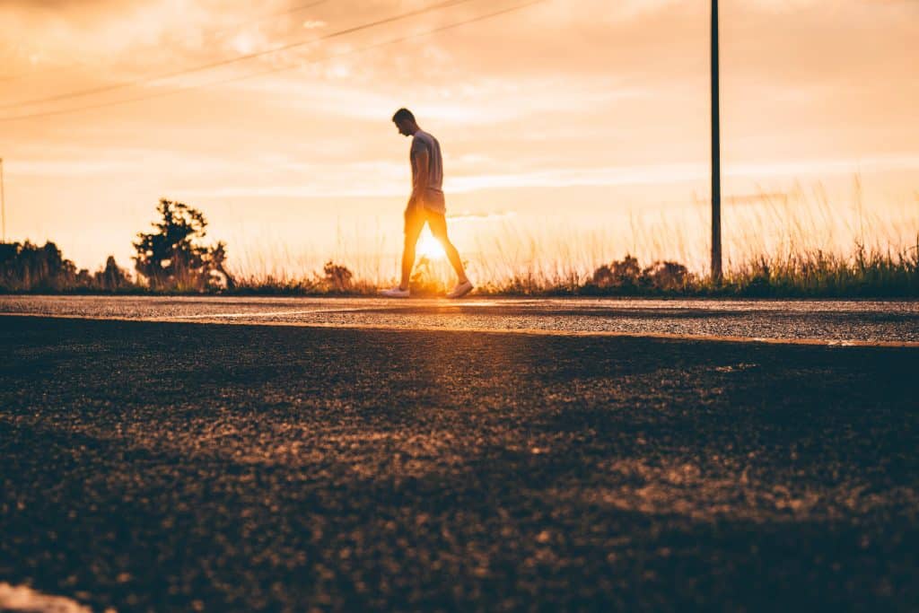 golden hour photography of man walking on asphalt road