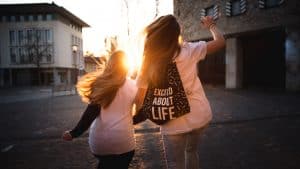 two women walking across the road during sunset