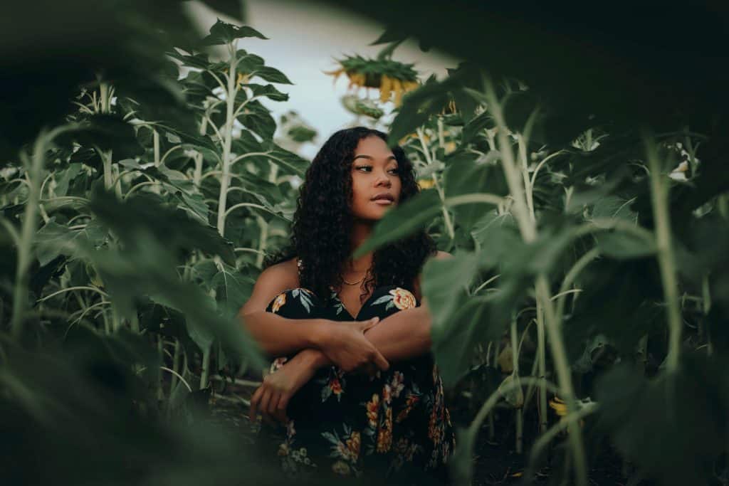 woman in black and brown floral dress standing in the middle of green plants