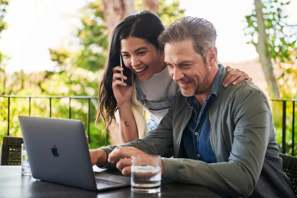 man sitting beside woman looking at laptop